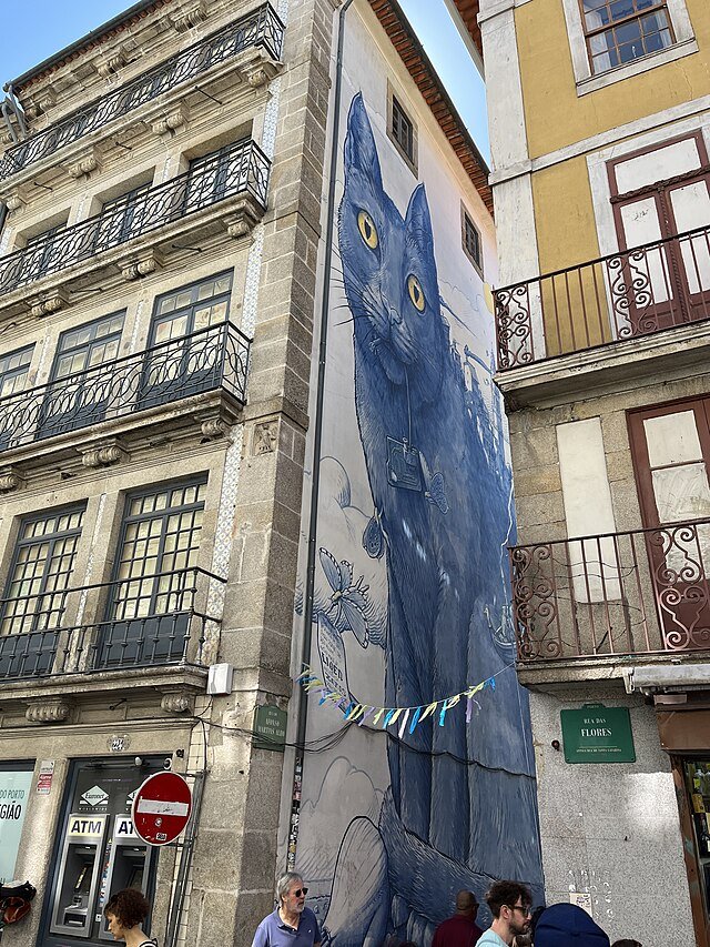 Grande fresque murale sur un mur d'immeuble représentant un chat bleu